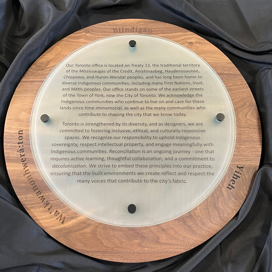 Round wooden plaque with engraved text on a black fabric background